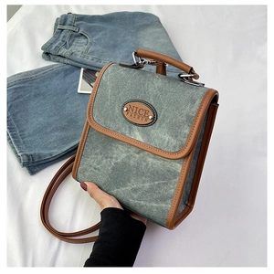 Detailed view of the gray denim bag featuring leather trim and a NICE FASHION patch