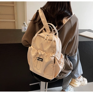 Detail of off-white nylon backpack featuring a drawstring front pocket and black label