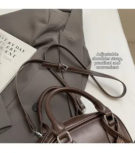 Close-up of brown leather bag with white contrast stitching and adjustable shoulder strap
