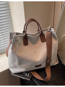 Minimalist nylon tote bag with brown leather handles and woven shoulder strap on desk