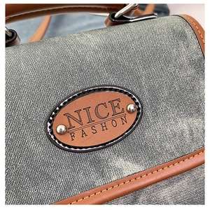 Detailed macro view of denim fabric texture with brown leather logo tag and silver rivets