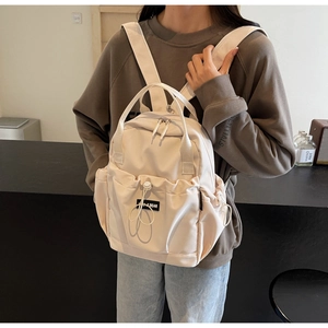 Detailed view of cream nylon backpack with YUJI BEAR label and drawstring pocket design