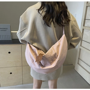 Detail of light pink nylon crescent bag showing fabric texture and double zipper pulls