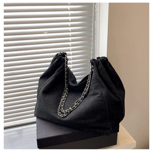 Macro shot of the black denim tote bag featuring a premium silver metal chain strap
