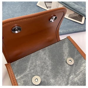 Detail of vintage denim and brown leather patchwork bag with magnetic buckles