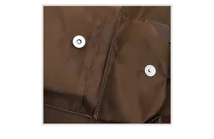 Macro detail of silver magnetic snaps and stitching on brown nylon tote bag