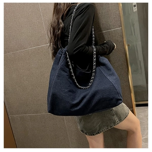 Detailed side view of large denim tote bag with silver chain strap on model