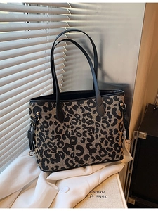 Leopard print tote bag with black leather handles shown on white clothing background