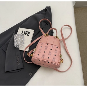 Detailed view of pink mini backpack with bear pattern and gold metal hardware on gray blazer