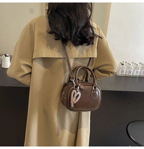 Detailed back view of a dark brown leather bowling bag with a cute heart charm