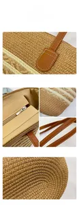 Close-up of woven straw tote bag with brown faux leather handles and white stitching details