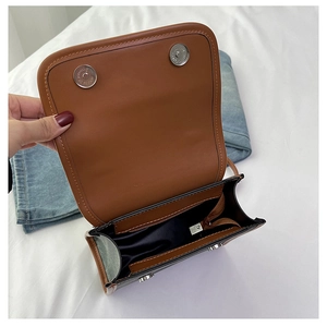 Detail of dual-color flap bag showing interior zipper pocket and magnetic buckles