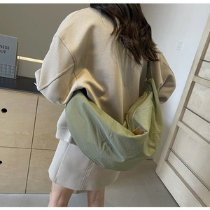 Sage green nylon crescent bag shown from side angle on shoulder for daily commute style