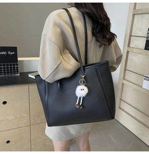 Dettaglio della borsa tote in pelle martellata nera con ciondolo a mostro in peluche
