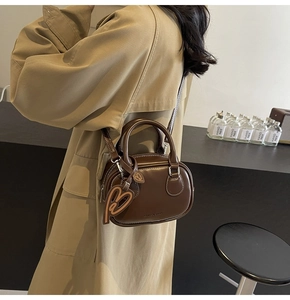 Brown leather bowling bag with heart charms and adjustable crossbody shoulder strap