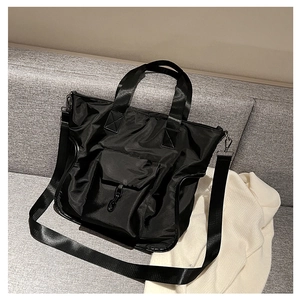 Detail of waterproof nylon tote bag with adjustable strap and front pocket on a sofa