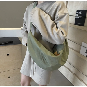 Detailed view of a green nylon dumpling bag worn by a model in a minimalist setting