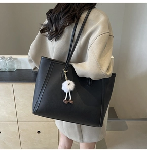 Dettaglio borsa tote nera in pelle martellata con ciondolo a mostro in peluche bianco