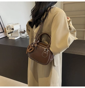 Close-up of brown bowling bag with white stitching and heart charm accessory