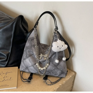 Detail of grey quilted hobo bag with silver chains, pearl charms and white plush cloud pendant