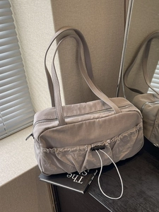 Chic pleated hobo bag in light grey with dual drawstring pockets on decorative book
