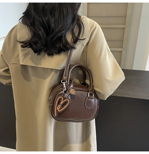 Detail view of deep brown leather bowling bag with heart charms and detachable strap