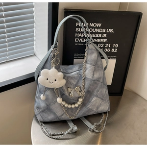 Detail of light blue denim tote bag with silver bow ornament and cloud plush pendant