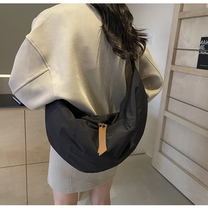 Close-up of black nylon crescent bag featuring gold zipper and brown leather puller