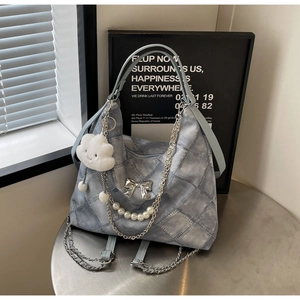Detail of light blue quilted tote bag with silver bow charm and pearl chain accent