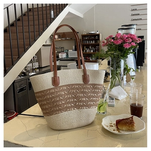Macro detail of bicolor straw tote bag with brown leather handles on a cafe counter