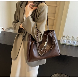 Detail of dark brown tote bag featuring braided straps and elegant pearl chain decor