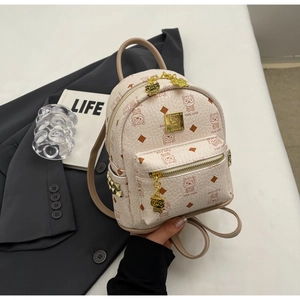 Detail of a beige mini backpack with cartoon prints, gold rivets, and a top handle