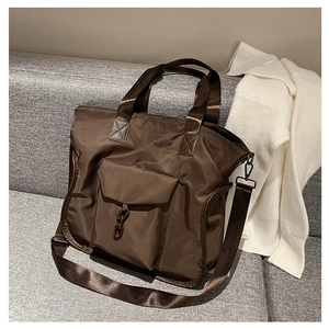 Detail of dark brown nylon tote bag with front flap pocket on a soft textured background