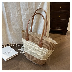 Detail of woven straw tote bag featuring brown leather straps and dual-tone texture