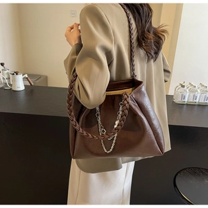 Detail of dark brown tote bag with woven shoulder strap and metal chain decoration