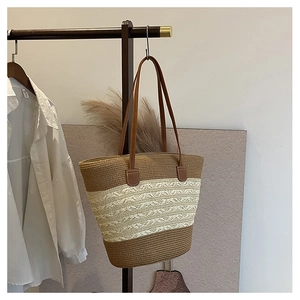 Close-up of handmade straw tote bag featuring brown and cream woven stripes and leather handles