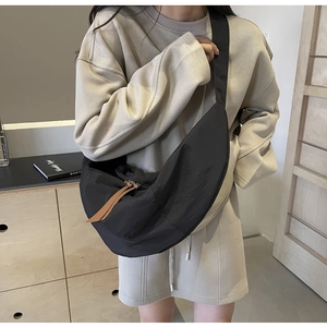 Detailed view of large black nylon crescent bag worn with a beige oversized hoodie