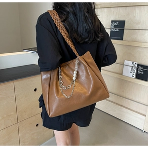 Detail of vintage brown tote bag with woven strap and decorative pearl floral chain