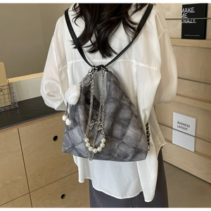 Close-up of quilted grey tote bag with bow charms and pearl chain detail