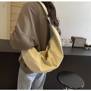 Rear view of large nylon crescent bag in beige worn as a stylish crossbody bag