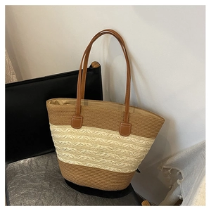 Detail of color-block straw tote bag with brown leather handles on a black chair