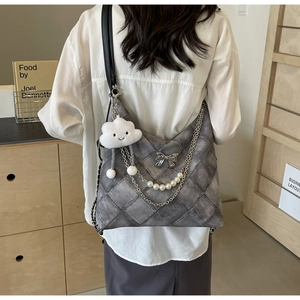 Detail of grey quilted tote bag with silver bow charm and elegant pearl chain strap
