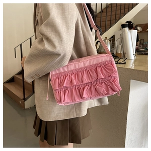 Rosafarbene Schultertasche mit Rüschen am Model getragen für einen schicken Look