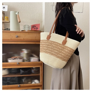 Detail of large woven beach tote featuring brown wave accent and durable leather shoulder strap