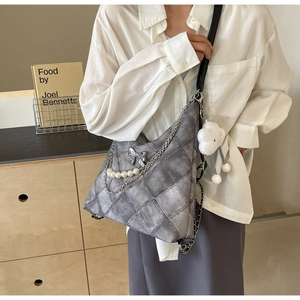 Detail of grey checkerboard tote bag with silver bow, pearls and plush cloud charm