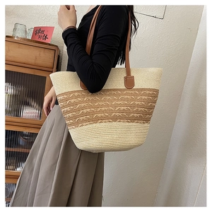 Detail of hand-woven straw tote bag with brown leather handles and wavy texture
