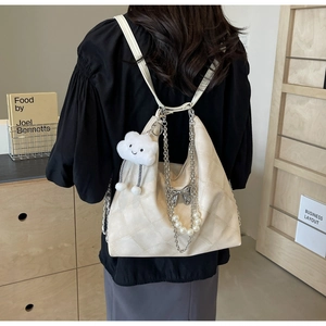 Detail of cream quilted tote bag with pearl chain strap and silver bow charm