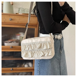 Detail der beige Nylon-Umhängetasche mit Rüschen an Model vor Retro-Hintergrund