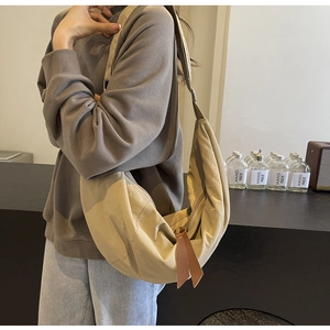 Detail of nylon crescent bag with brown leather zipper pull and khaki texture