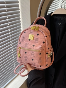 Pink mini faux leather backpack with cat owl prints and gold studs in a fashion setting